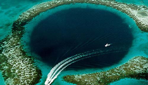 A boat is traveling through a blue hole near Staniel Cay in the ocean.