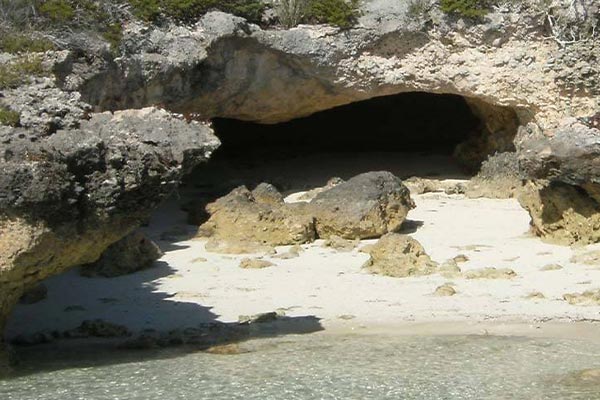 The entrance to a cave on a sandy beach in Staniel Cay.