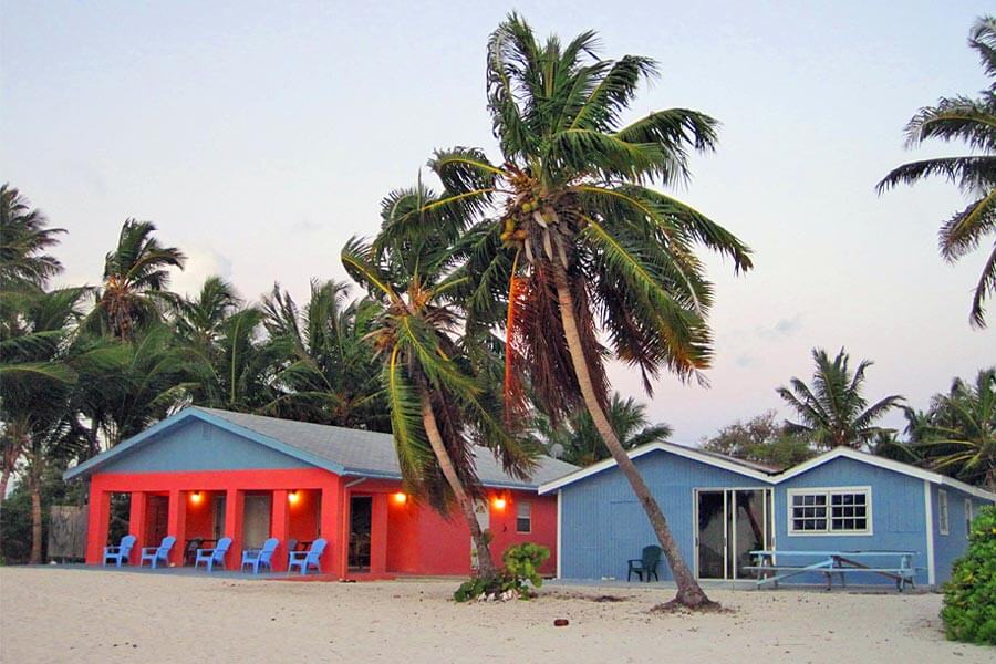 A blue and red house with palm trees in the background in Staniel Cay.