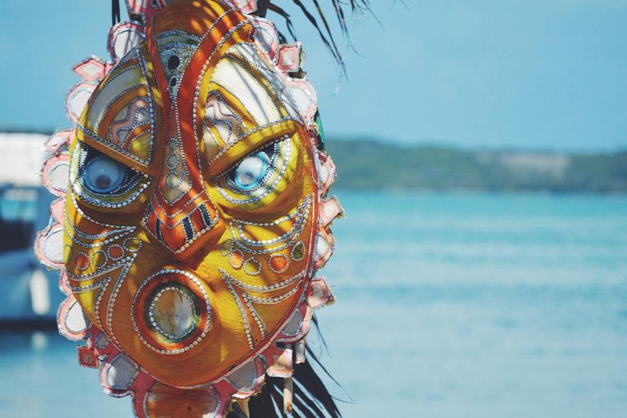 A colorful mask hanging from a palm tree near the water in the Bahamas.