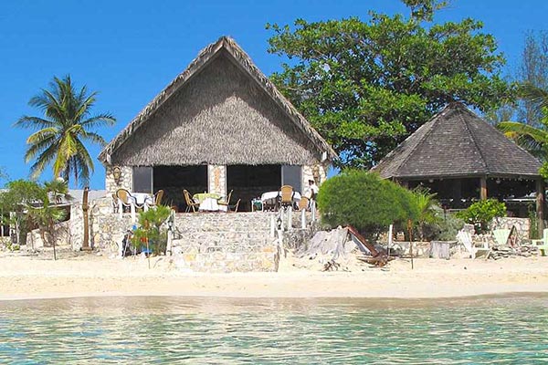 a-thatched-hut-sits-on-the-beach-next-to-a-palm-tree-in-andros