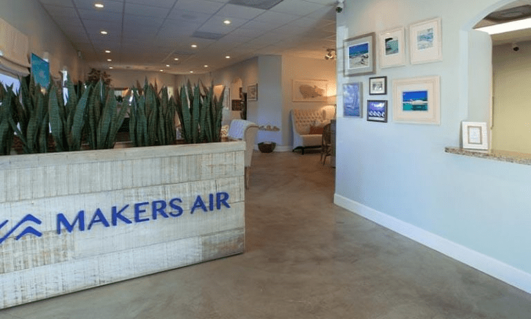 Lobby interior with plants, art on walls, and 'MAKERS AIR' sign.