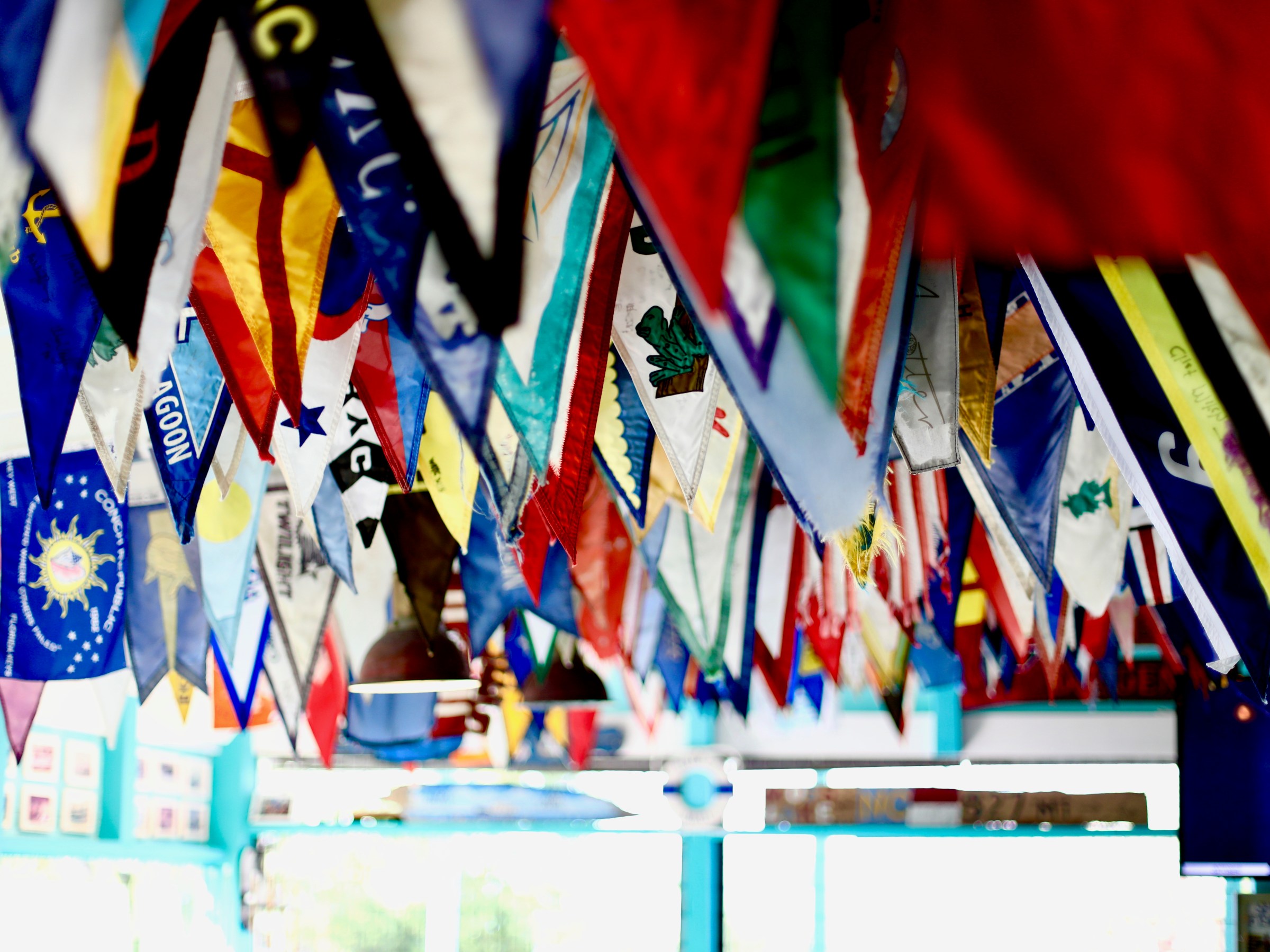 Colorful nautical flags hanging from the ceiling, creating a festive atmosphere in an indoor space.