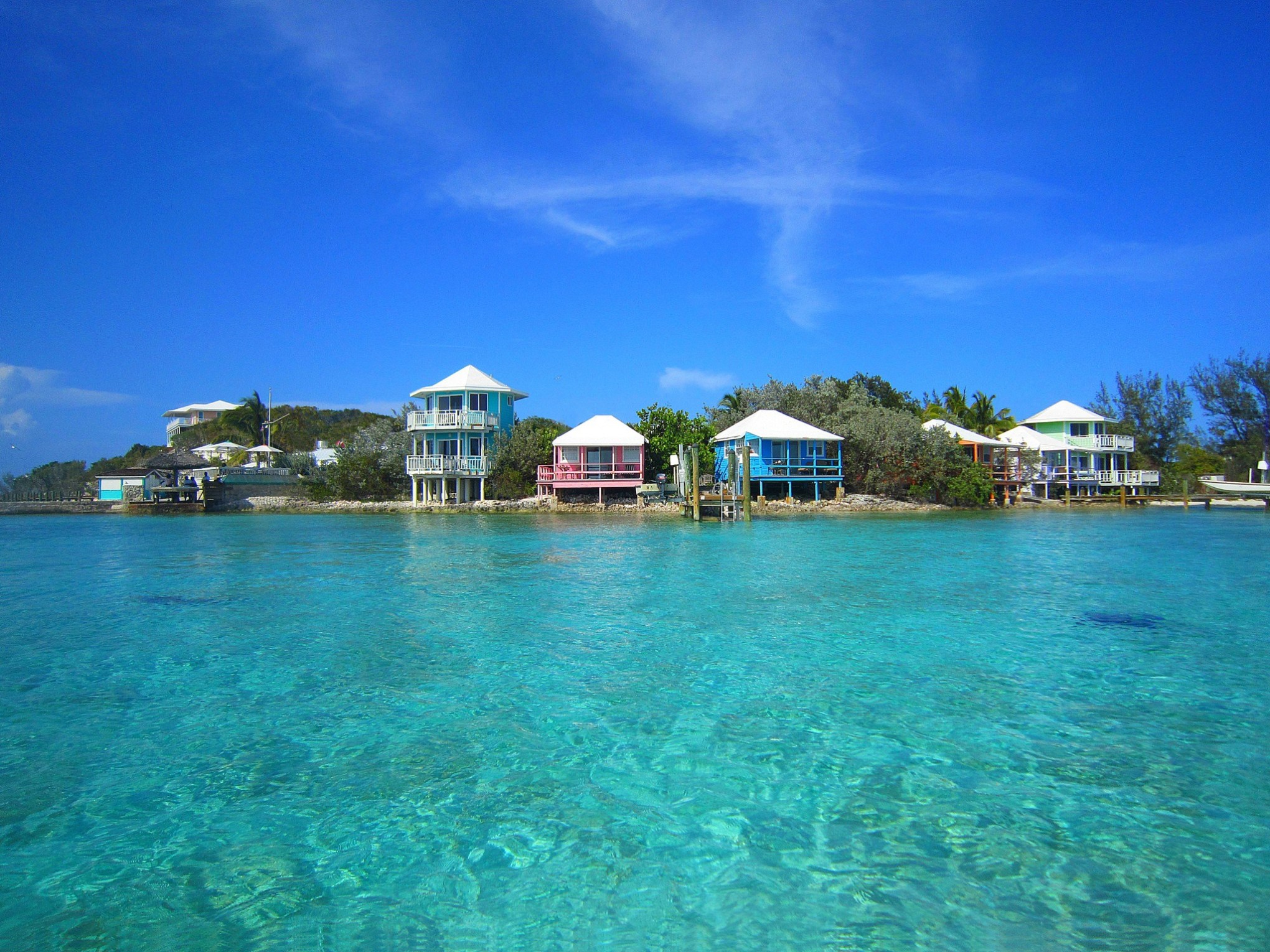 Colorful houses by clear blue water under a bright blue sky.