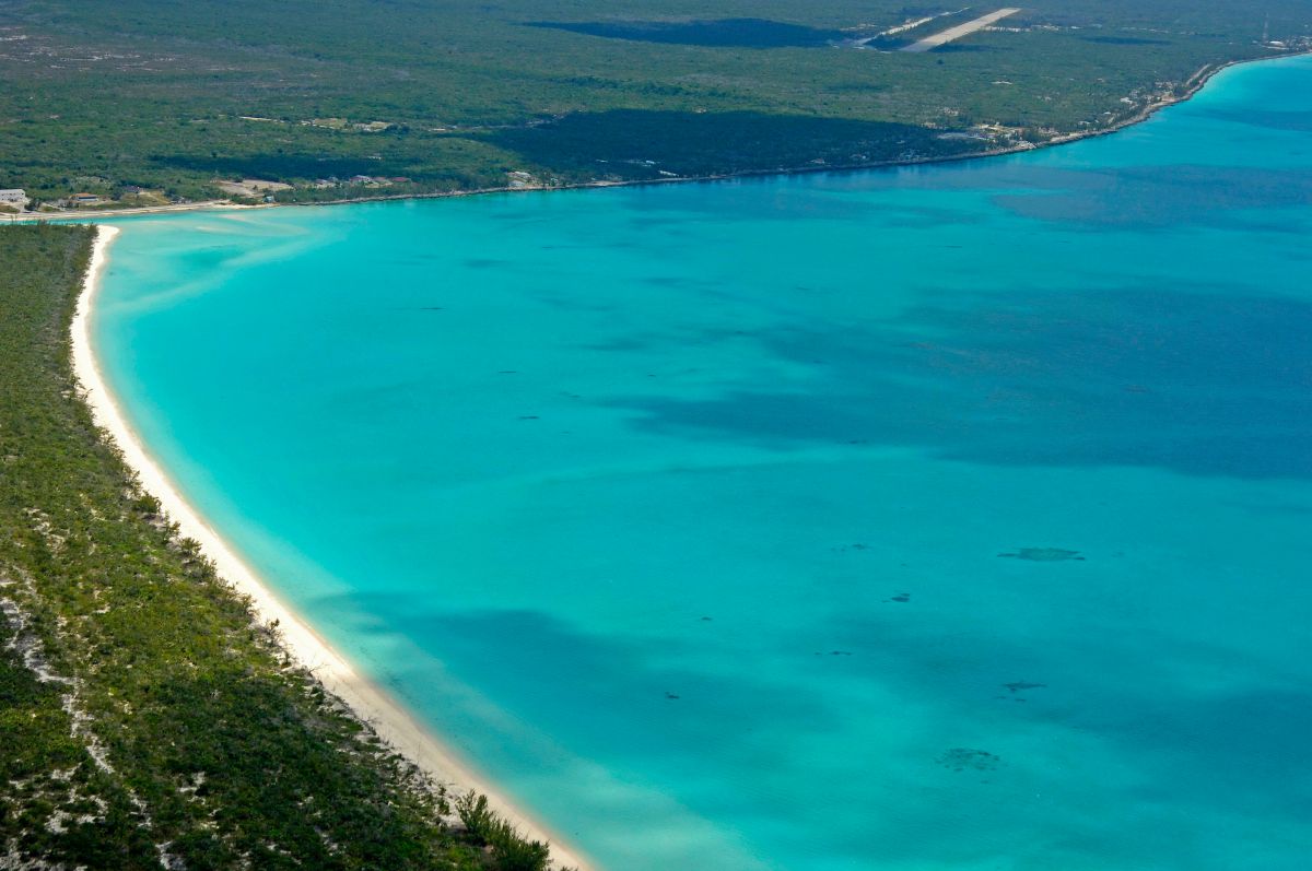Aerial view of a coastline with turquoise waters and lush greenery.